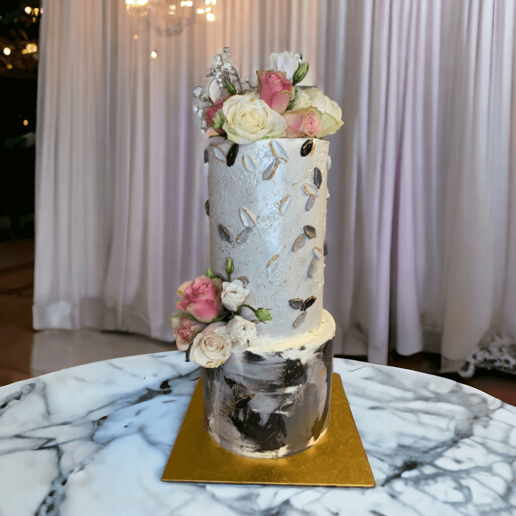 Torta moderna di matrimonio a due piani con finitura marmorizzata, dettagli in oro e decorazioni floreali eleganti