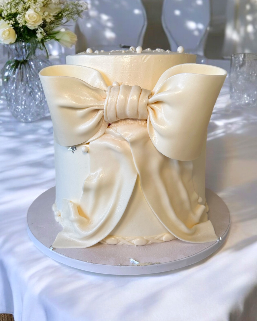 Torta elegante con fiocco in pasta di zucchero color avorio, ispirata a un abito da cerimonia