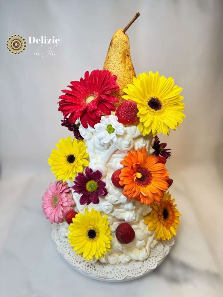 Torta artistica decorata con panna, frutta fresca e fiori colorati, con pera intera come topper