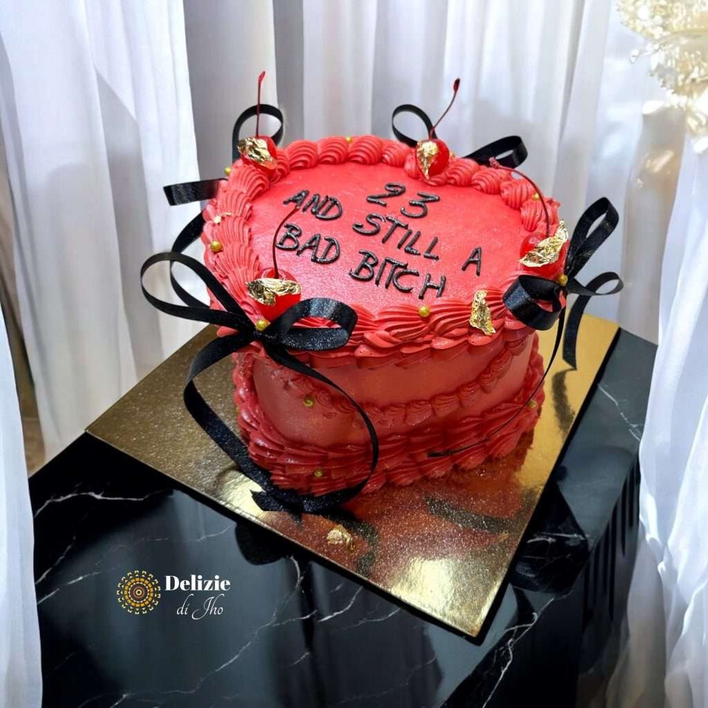 Lambeth Cake rossa a cuore con ciliegie dorate, fiocchi neri e scritta ironica